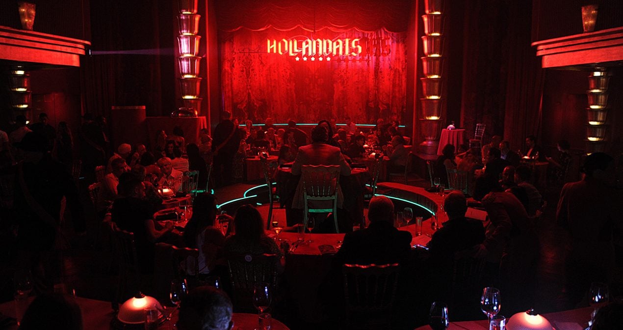 crowd sits in red lit room looking at the Faena Theater stage